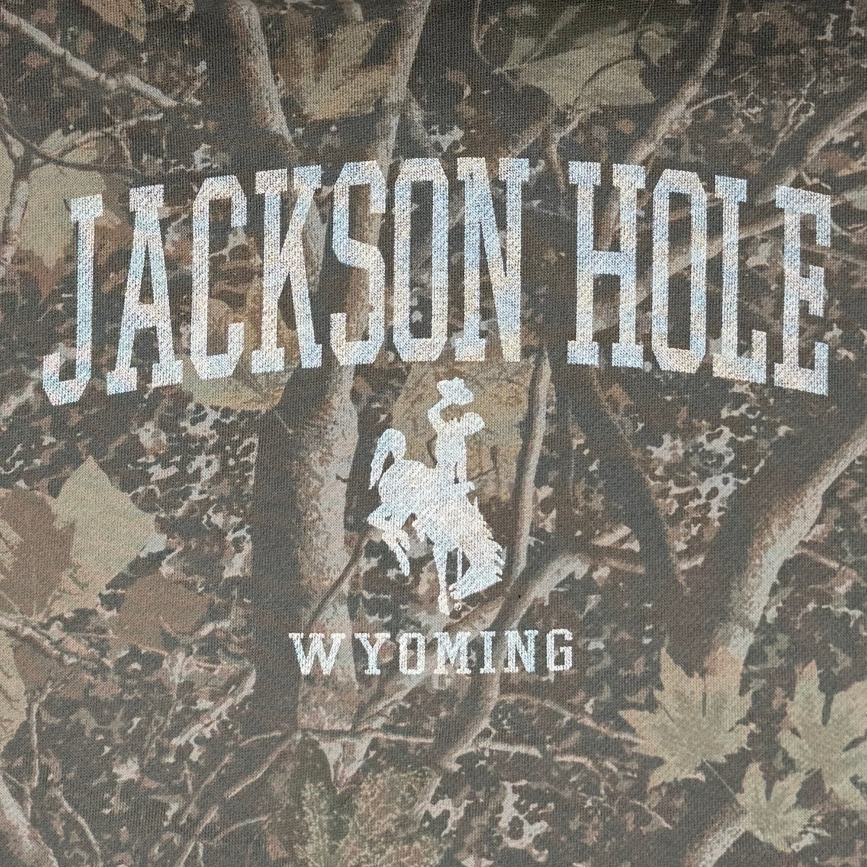 Camouflage hoodie with 'Jackson Hole Wyoming' text on a white background