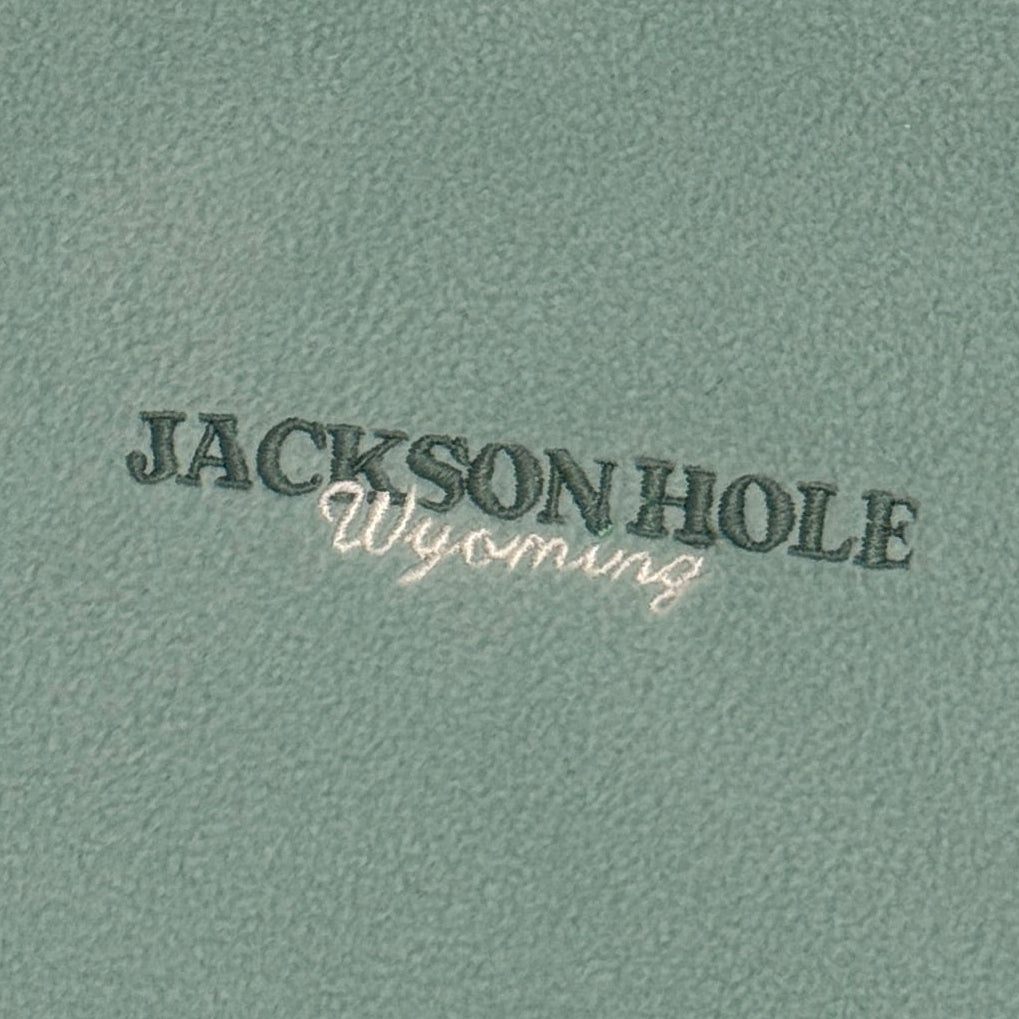 Green fleece jacket with 'Jackson Hole' branding on a white background