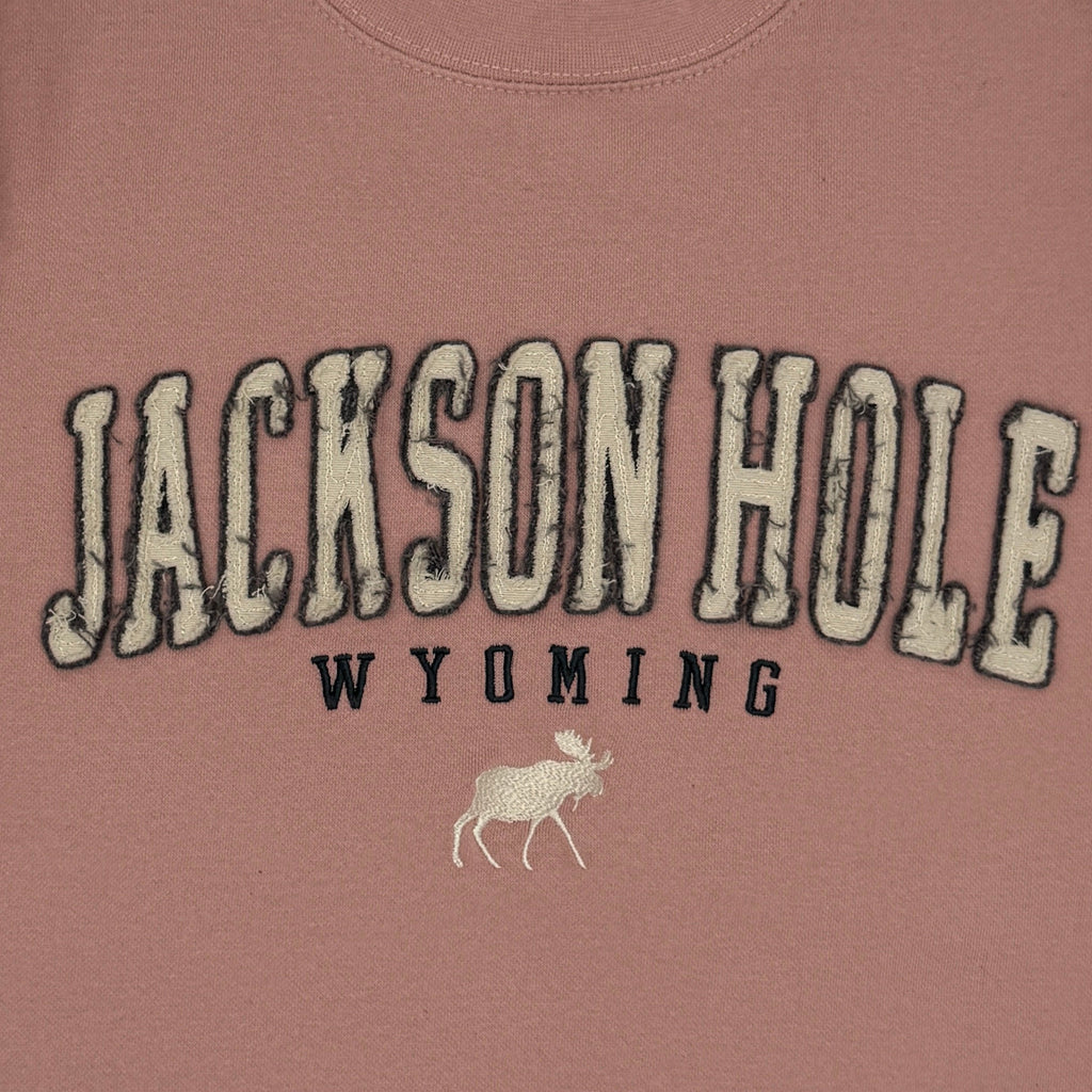 Pink sweatshirt with 'Jackson Hole Wyoming' text on a white background